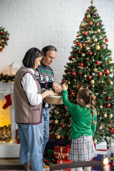 Meisje Versieren Kerstboom Met Interraciale Grootouders Woonkamer — Stockfoto