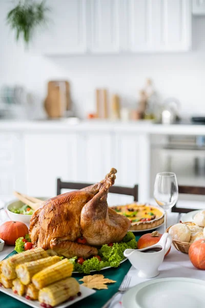 thanksgiving dinner with traditional roasted turkey and grilled corn in blurred kitchen