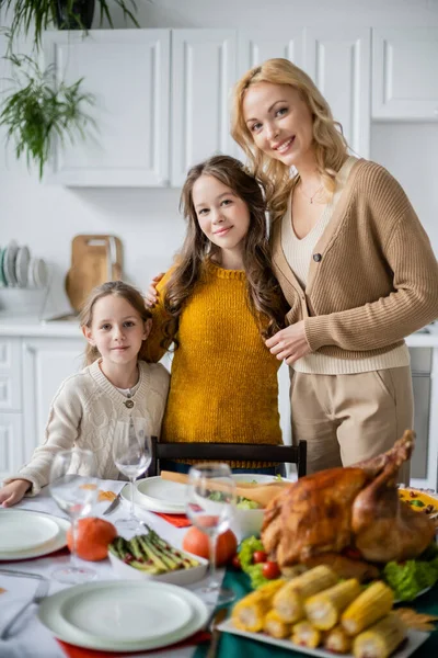 おいしい感謝祭の晩ご飯と一緒にカメラのそばのテーブルで笑っている母親と娘 — ストック写真