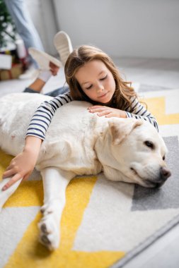 Evde yerde yatarken Labrador 'a sarılan kız. 