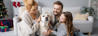 Mutlu aile evcil labrador köpeği yeni yıl boyunca oturma odasında, pankartta 