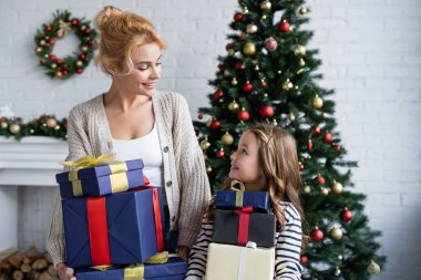 Mutlu anne ve kız Noel hediyelerini evde tutuyorlar. 