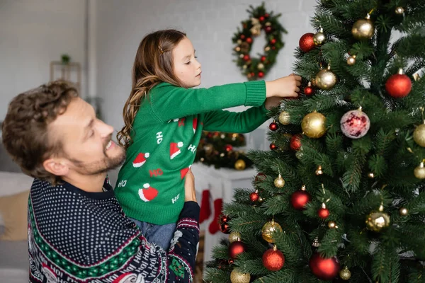 Leende Man Håller Dotter Dekorera Julgran Hemma — Stockfoto