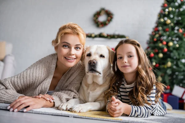 Positiv Mor Och Barn Tittar Kameran Nära Labrador Hemma — Stockfoto