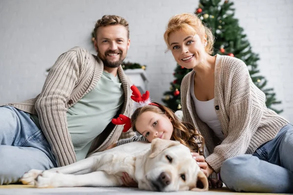 Pozitív Szülők Néz Kamera Közelében Lánya Karácsonyi Fejpánt Labrador Padlón — Stock Fotó