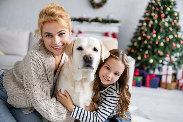 Gyerek Átöleli Labrador Közel Anya Nézi Kamera Karácsonykor Otthon — Stock Fotó