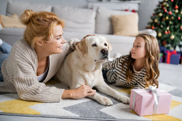 Mujer Alegre Acariciando Labrador Cerca Hija Regalo Navidad Suelo Casa — Foto de Stock