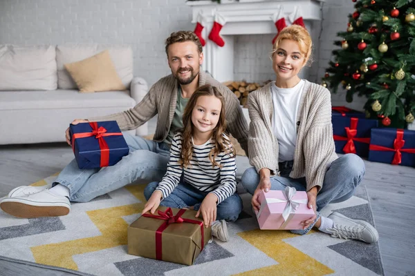 Positive Family Holding New Year Presents Looking Camera Carpet Home — Stock Photo, Image