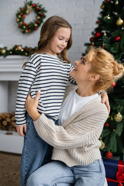 Positive Frau Warmer Strickjacke Umarmt Lächelnde Tochter Bei Neujahrsfeier Hause — Stockfoto