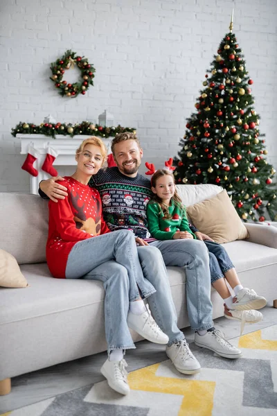 Família Positiva Suéteres Abraçando Sofá Perto Decoração Natal Borrada Casa — Fotografia de Stock