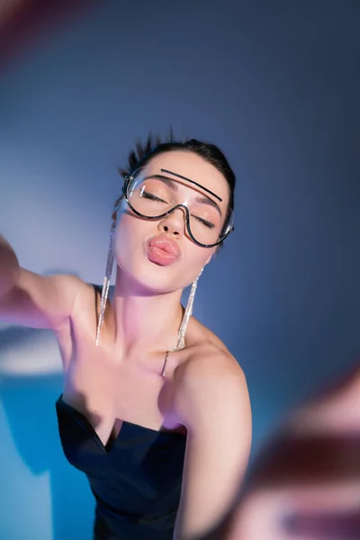 Şeffaf Gözlüklü Genç Bir Kadının Mavi Arka Planda Dudaklarını Somurtması — Stok fotoğraf