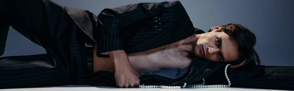 Homem Elegante Morena Terno Com Pérolas Deitado Enquanto Posando Cinza — Fotografia de Stock