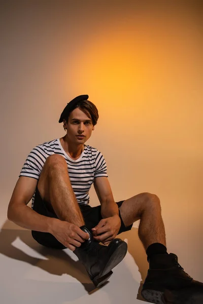 Elegante Uomo Berretto Shirt Righe Seduta Mentre Lega Lacci Delle — Foto Stock
