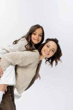 Mutlu anne ve kız örgü örüp kameraya bakarken gri renkte izole edilmiş eğleniyorlar.