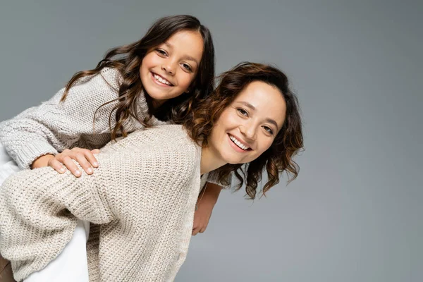 Giovane Donna Abiti Caldi Piggybacking Figlia Mentre Guardando Fotocamera Isolata — Foto Stock