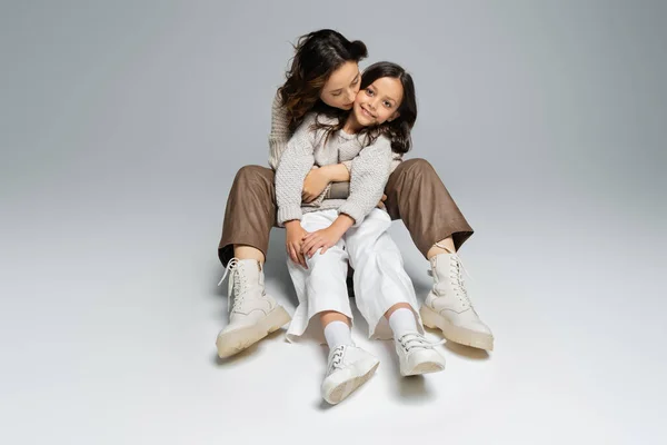 Full Length Stylish Woman Embracing Daughter While Sitting Grey Background — Stock Photo, Image