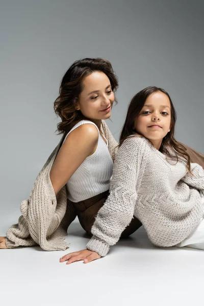 Mutlu kadın gri arka planda otururken modaya uyan kızına bakıyor