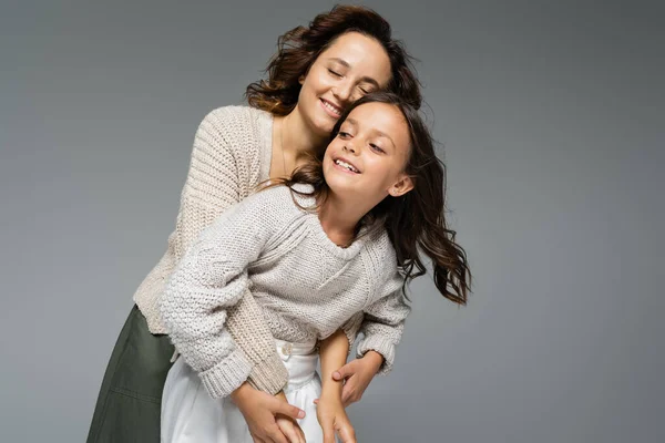 一个快乐的女人 紧闭双眼 抱着女儿 穿着温暖的针织衫 与灰色隔离 — 图库照片