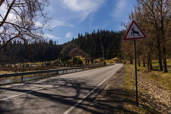 Straßenschild nahe leerer Straße und Berge im Hintergrund — Stockfoto