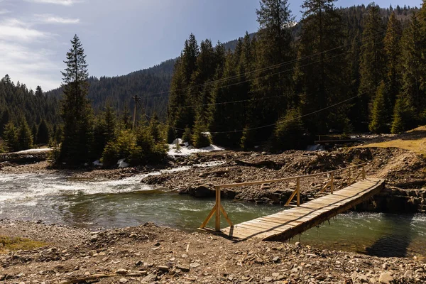 Wooden bridge above river in mountains — Photo de stock