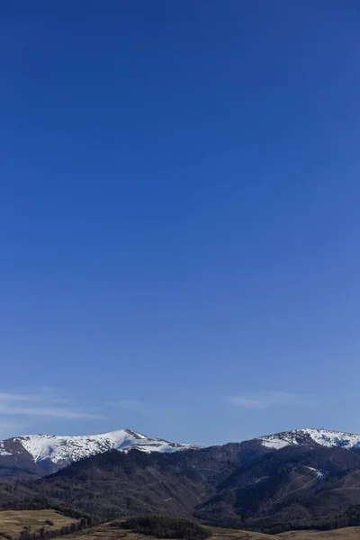 Пейзаж с горами на фоне снега и голубого неба — стоковое фото