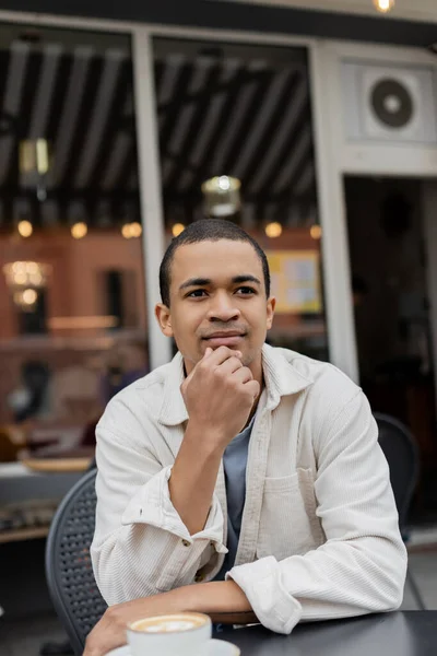 Retrato del hombre afroamericano pensativo sentado en la terraza de verano - foto de stock