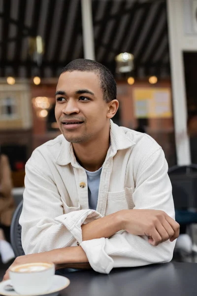 Portrait of dreamy african american man sitting on summer terrace — Stock Photo