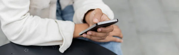 Vue partielle de l'homme afro-américain textos sur smartphone à l'extérieur, bannière — Photo de stock