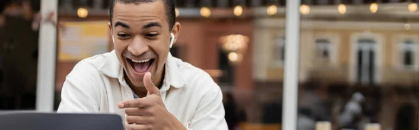 Glücklich afrikanisch-amerikanischer Mann gestikuliert während Videoanruf auf Sommerterrasse in Café, Banner — Stockfoto