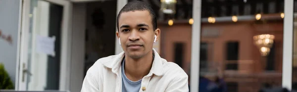 Afro-américain freelance dans les écouteurs sans fil écouter de la musique sur la terrasse d'été, bannière — Photo de stock