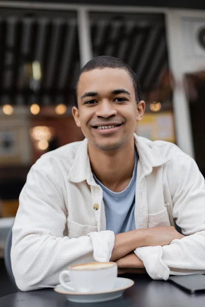 Усміхнений і молодий афроамериканський чоловік дивиться на камеру на літній терасі — стокове фото