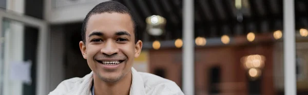 Smiling and young african american man looking at camera outside, banner — Stock Photo