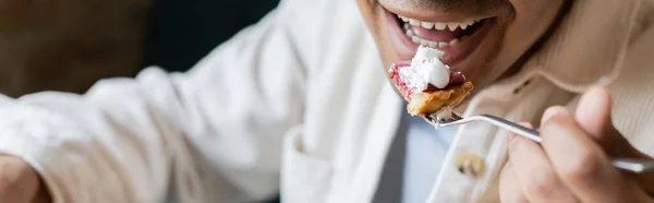 Vue recadrée de heureux homme afro-américain mangeant un gâteau savoureux dans un café, bannière — Photo de stock