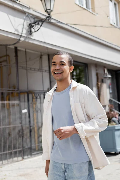 Lächelnder afrikanisch-amerikanischer Mann in Hemdjacke läuft auf der Straße — Stockfoto