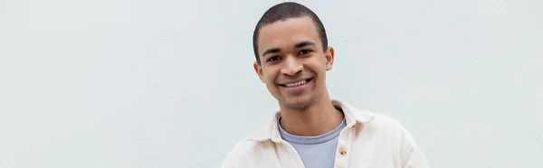 Heureux homme afro-américain souriant tout en regardant la caméra à l'extérieur, bannière — Photo de stock