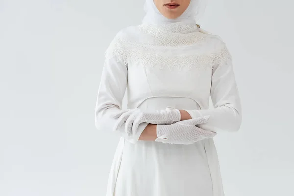 Cropped view of young muslim bride in gloves and white dress isolated on grey — Stock Photo