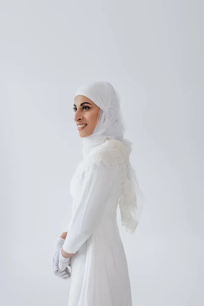 Mujer musulmana feliz en hijab y vestido de novia aislado en gris - foto de stock