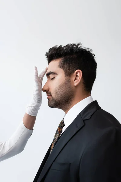 Bride in white glove touching forehead of groom during wedding ceremony isolated on grey — Stock Photo