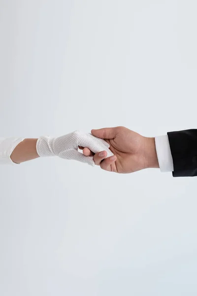 Vue recadrée du marié et de la mariée dans un gant tenant les mains isolées sur du gris — Photo de stock