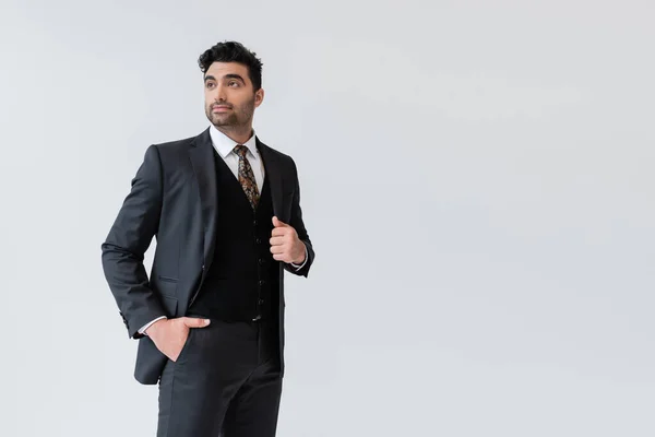 Muslim groom in formal wear standing with hand in pocket isolated on grey — Stock Photo