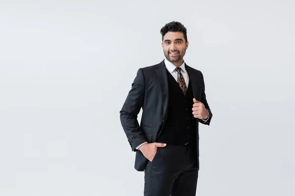 Happy muslim man in formal wear standing with hand in pocket isolated on grey — Stock Photo