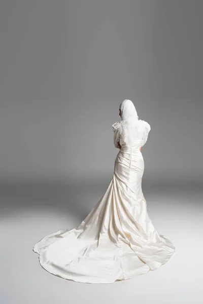 Vue arrière de la mariée musulmane en robe de mariée magnifique debout sur gris — Photo de stock