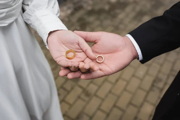 High angle view of groom and bride holding wedding rings in hands — Stock Photo