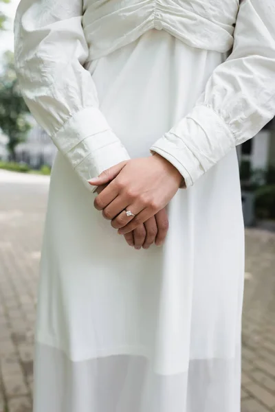 Vista recortada de la novia en vestido de novia con anillo de diamantes en el dedo de pie fuera - foto de stock