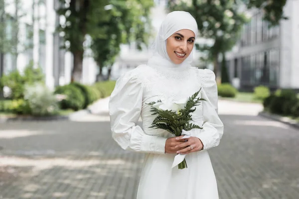 Joyful muslim bride with diamond ring on finger holding wedding bouquet — Stock Photo