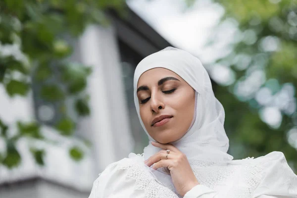 Portrait of muslim bride in hijab with diamond ring on finger and closed eyes — Stock Photo