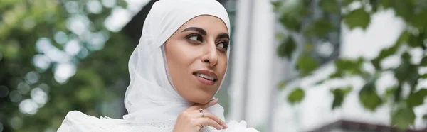 Vue à angle bas de la mariée musulmane en hijab avec bague en diamant sur le doigt regardant loin, bannière — Photo de stock
