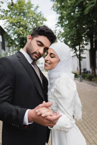 Heureux musulmans jeunes mariés avec les yeux fermés tenant la main — Photo de stock