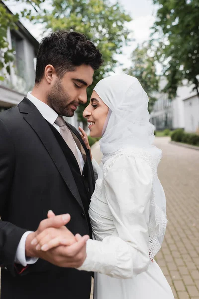 Glückliche muslimische Braut und Bräutigam mit geschlossenen Augen Händchen haltend — Stockfoto