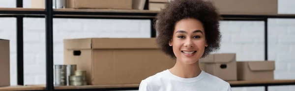Young and pretty african american woman looking at camera in volunteer center, banner — Stock Photo